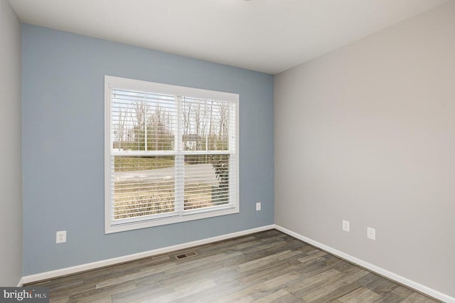 unfurnished room featuring visible vents, wood finished floors, and baseboards