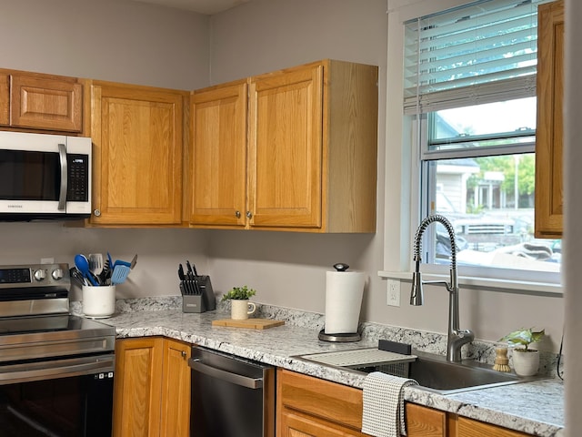 kitchen featuring stainless steel appliances, light stone countertops, and sink