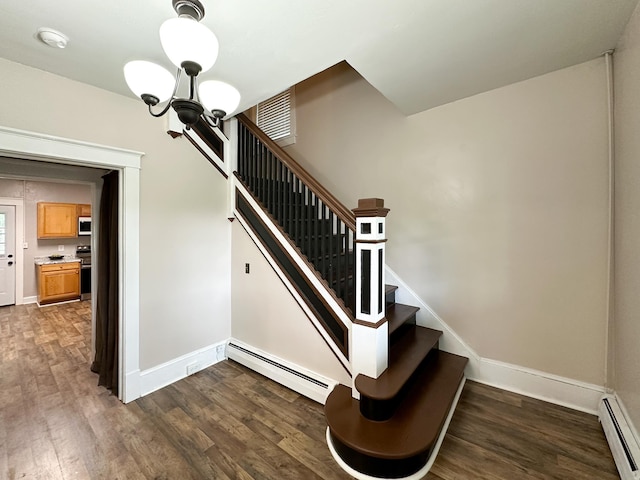 stairway featuring baseboard heating, an inviting chandelier, and hardwood / wood-style floors