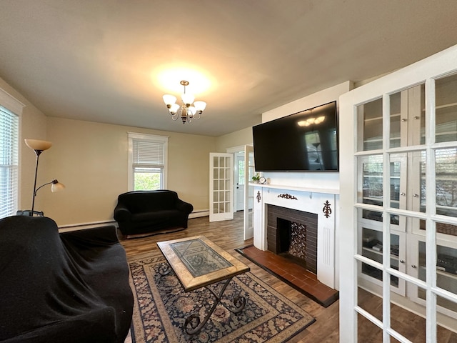 living room featuring a brick fireplace, dark wood-type flooring, a baseboard radiator, and a chandelier