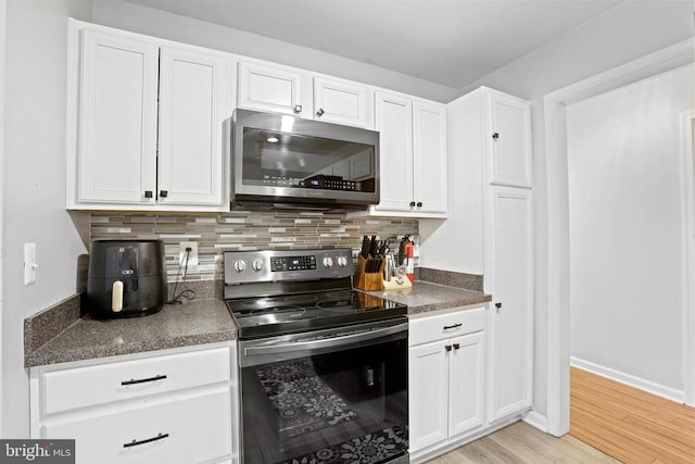 kitchen featuring white cabinets, appliances with stainless steel finishes, and backsplash