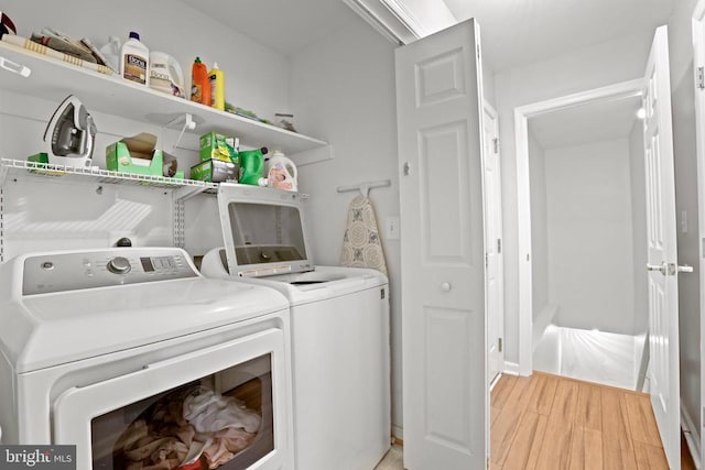 laundry area with light hardwood / wood-style flooring and washer and clothes dryer