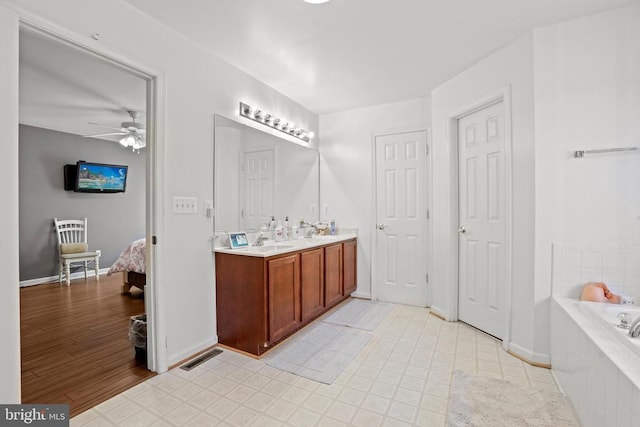 bathroom with tiled bath, vanity, hardwood / wood-style floors, and ceiling fan