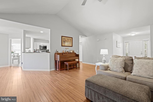 living room with light hardwood / wood-style flooring, ceiling fan, and vaulted ceiling