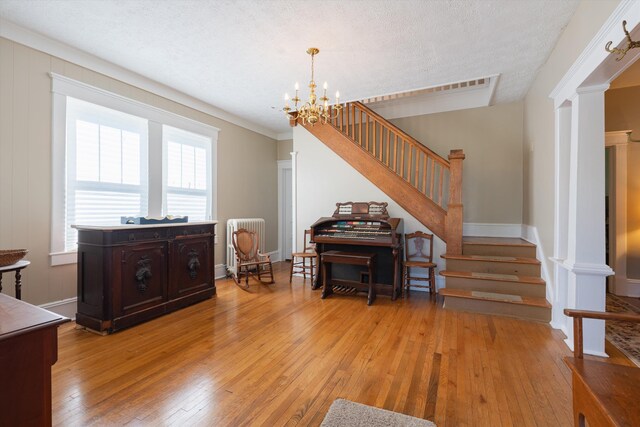 interior space with light hardwood / wood-style floors, a textured ceiling, and a notable chandelier