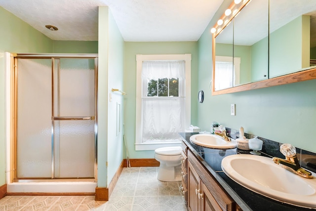 bathroom featuring vanity, a textured ceiling, a shower with door, and toilet