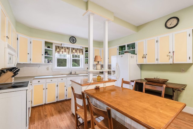 kitchen with white cabinetry, sink, white appliances, and ornate columns