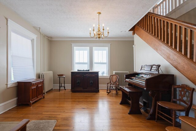 misc room with an inviting chandelier, radiator heating unit, a textured ceiling, and light wood-type flooring