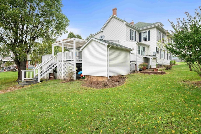 rear view of house with a wooden deck and a yard