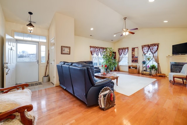 living room with ceiling fan, lofted ceiling, and light hardwood / wood-style flooring