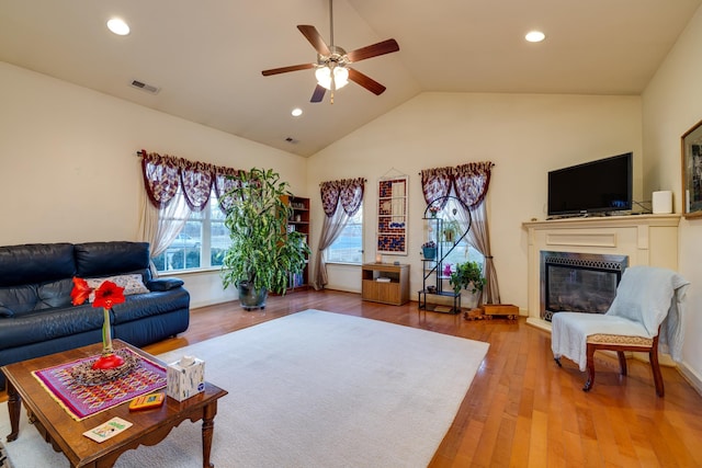 living room featuring wood-type flooring, ceiling fan, and vaulted ceiling