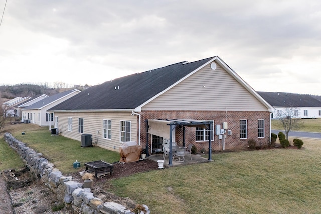 rear view of house with an outdoor fire pit, a yard, a patio area, and central air condition unit