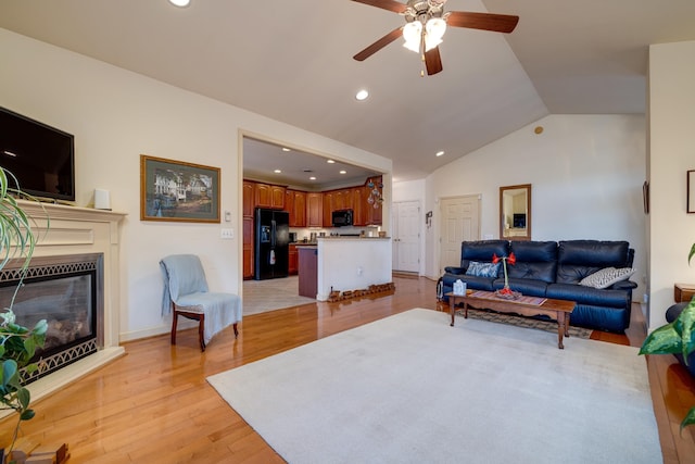 living room with lofted ceiling, ceiling fan, and light hardwood / wood-style flooring