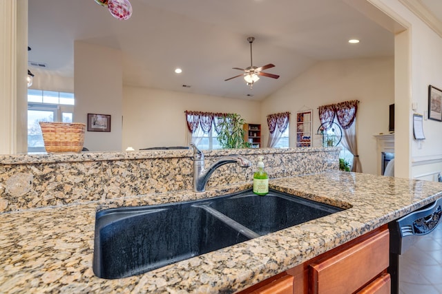 kitchen featuring sink, light stone counters, vaulted ceiling, dishwasher, and ceiling fan