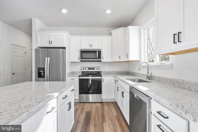 kitchen with dark wood-type flooring, sink, light stone counters, stainless steel appliances, and white cabinets