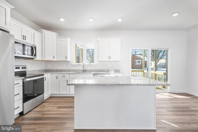 kitchen with sink, light stone counters, a center island, appliances with stainless steel finishes, and white cabinets