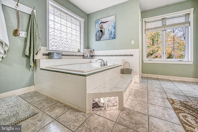 bathroom featuring tile patterned flooring, a garden tub, plenty of natural light, and baseboards