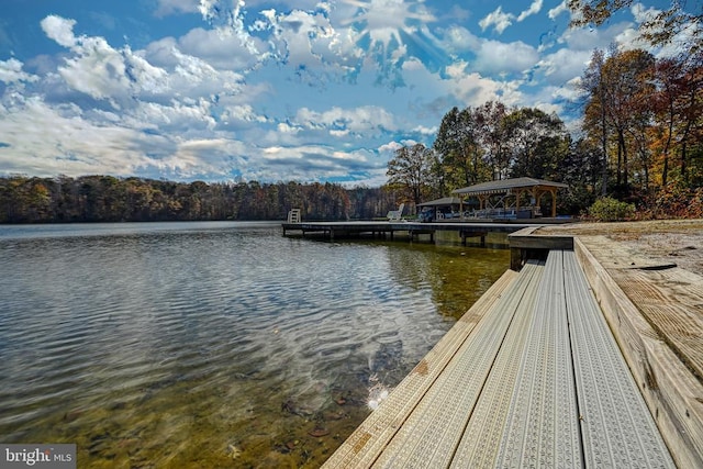 view of dock with a gazebo, a water view, and a forest view