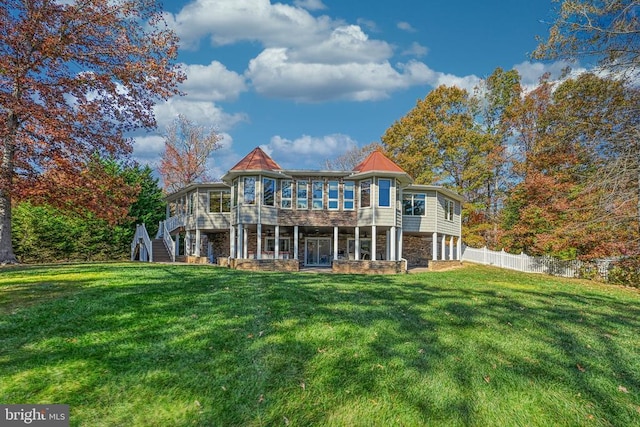 back of property featuring stone siding, a yard, stairway, and fence