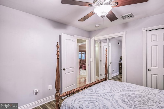 bedroom with multiple closets, baseboards, visible vents, and wood finished floors