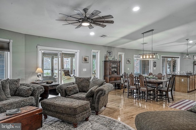 living area with a ceiling fan, recessed lighting, visible vents, and light wood finished floors