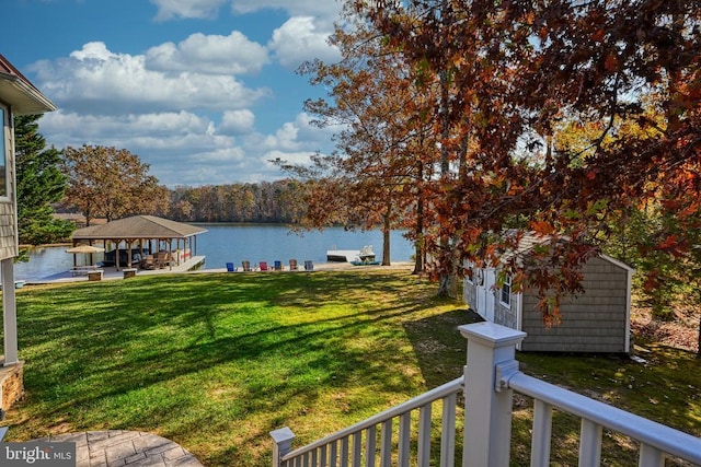 view of yard featuring a water view, a gazebo, a shed, and an outbuilding