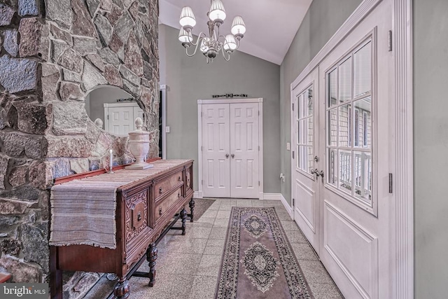 foyer entrance featuring lofted ceiling, granite finish floor, baseboards, and a chandelier