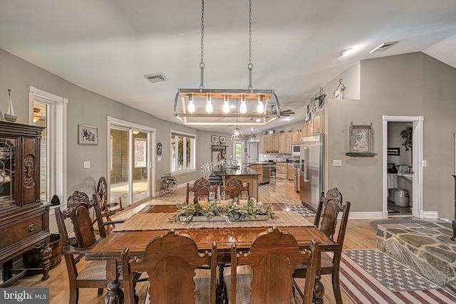 dining space featuring vaulted ceiling, light wood finished floors, visible vents, and baseboards