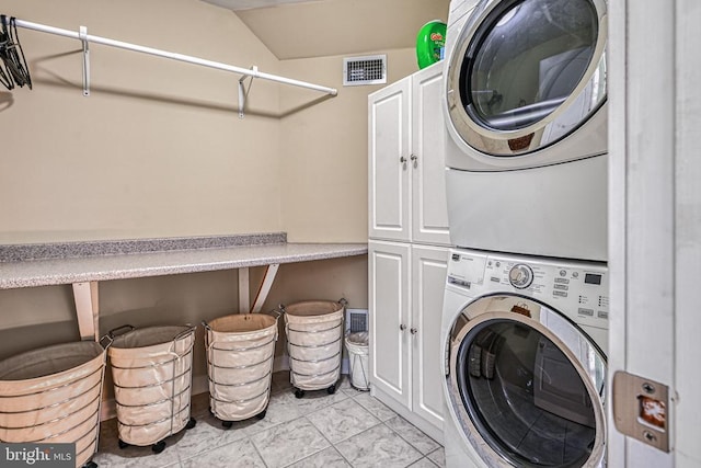 washroom with cabinet space, visible vents, and stacked washer and dryer