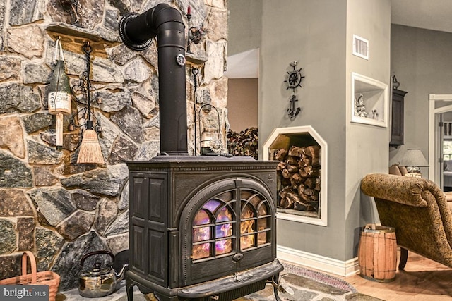 room details with a wood stove, baseboards, visible vents, and wood finished floors