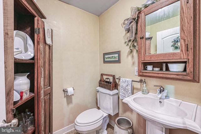 half bath with baseboards, a sink, and toilet