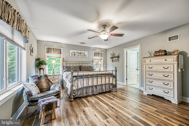 bedroom featuring ceiling fan, wood finished floors, visible vents, and baseboards