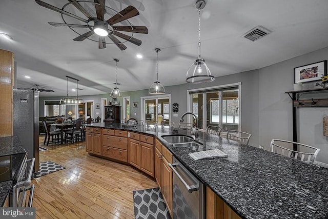 kitchen featuring stainless steel appliances, a sink, visible vents, light wood-type flooring, and brown cabinets