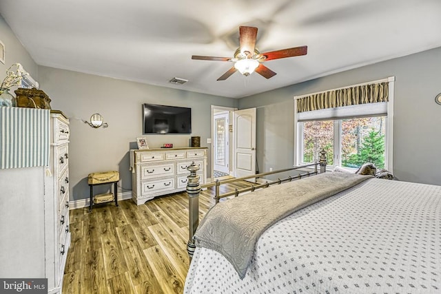 bedroom with ceiling fan, wood finished floors, visible vents, and baseboards