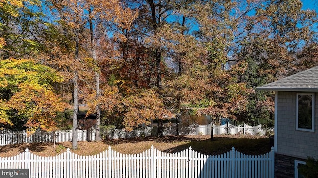 view of property exterior featuring roof with shingles and fence