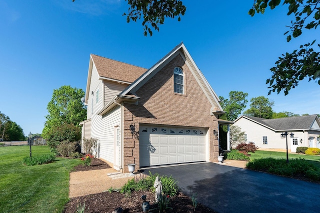view of side of home featuring a lawn, brick siding, an attached garage, and aphalt driveway