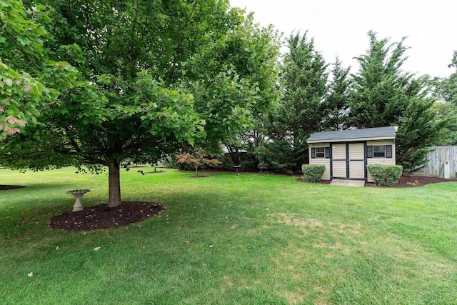 view of yard featuring fence, a storage unit, and an outbuilding