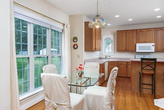 kitchen with light wood finished floors, white appliances, light countertops, recessed lighting, and decorative light fixtures