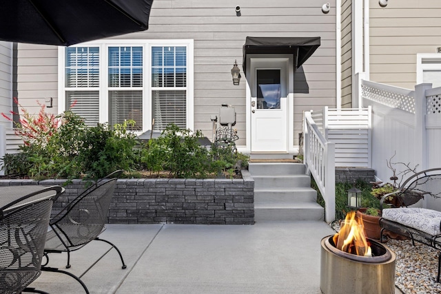 view of exterior entry with a patio area and fence