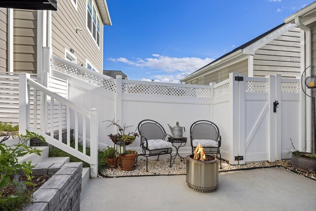 view of patio / terrace featuring fence, a fire pit, and a gate