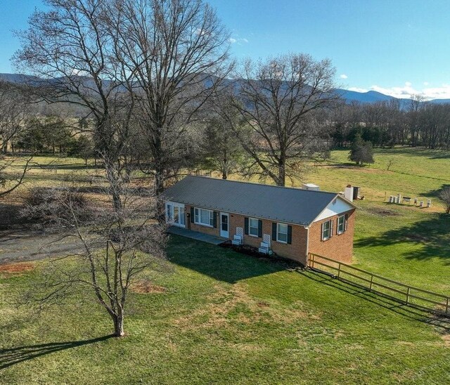 single story home with a rural view, a mountain view, and a front yard