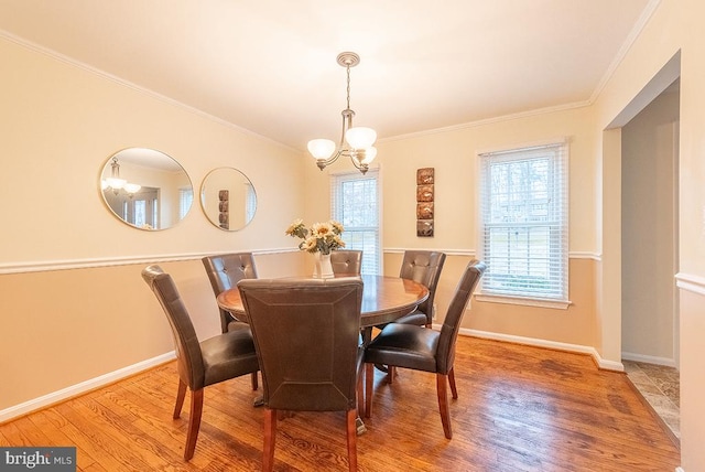 dining space with baseboards, a chandelier, wood finished floors, and ornamental molding