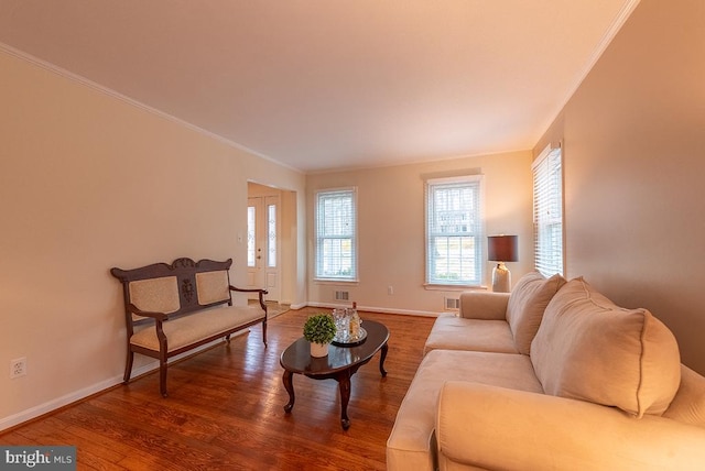 living room featuring ornamental molding, visible vents, baseboards, and wood finished floors