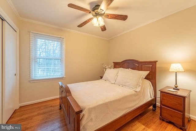 bedroom with a ceiling fan, baseboards, ornamental molding, a closet, and light wood-type flooring