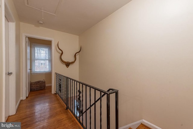 hallway with attic access, baseboards, and light wood finished floors