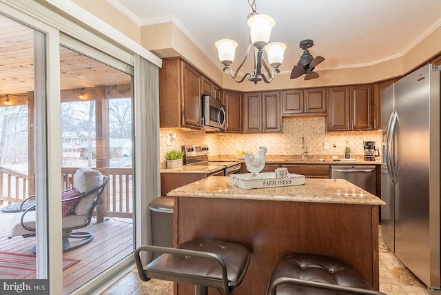 kitchen with decorative backsplash, a kitchen island, appliances with stainless steel finishes, ornamental molding, and a sink