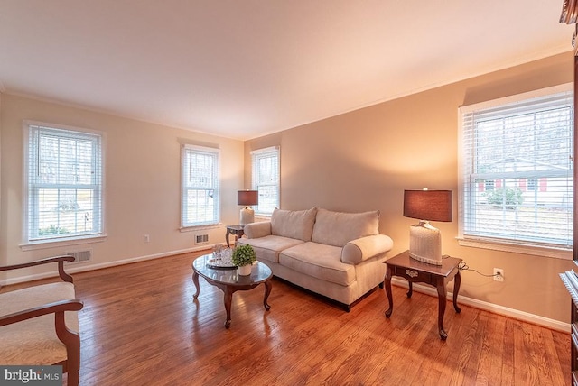 living area with baseboards, visible vents, and wood finished floors