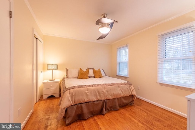 bedroom with ornamental molding, a closet, baseboards, and light wood finished floors