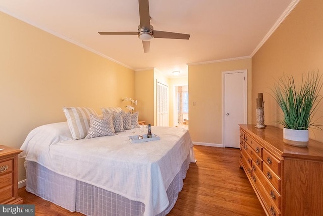 bedroom with a closet, ornamental molding, a ceiling fan, wood finished floors, and baseboards