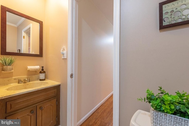 bathroom featuring ornamental molding, vanity, baseboards, and wood finished floors